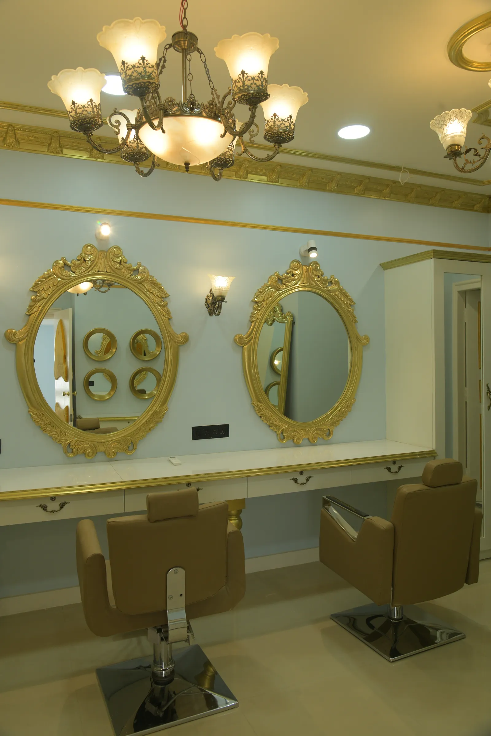 Gold-framed mirror stations and styling chairs at Le Beau